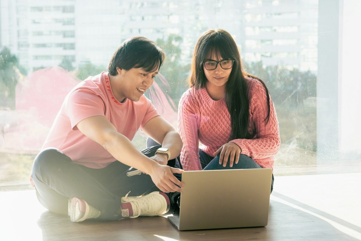 A couple sitting on the floor looking at a laptop