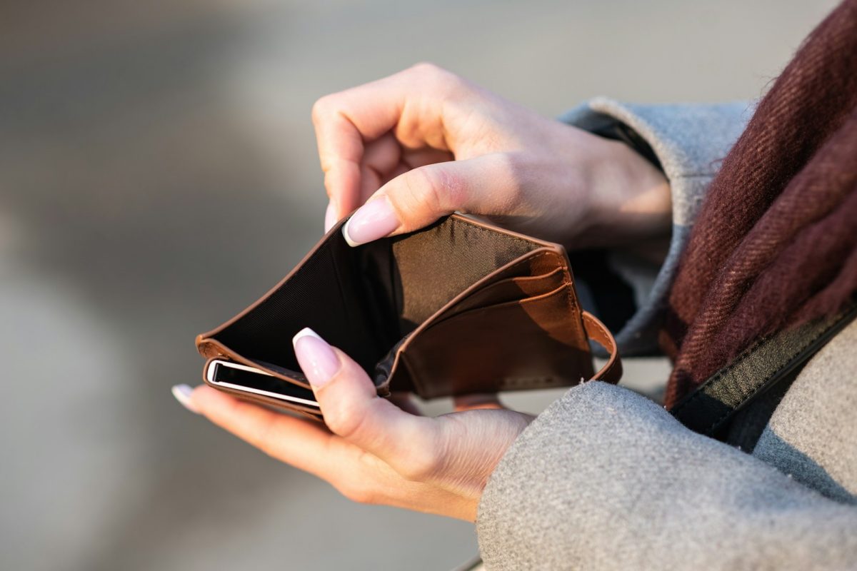 Hands holding an empty wallet and a phone