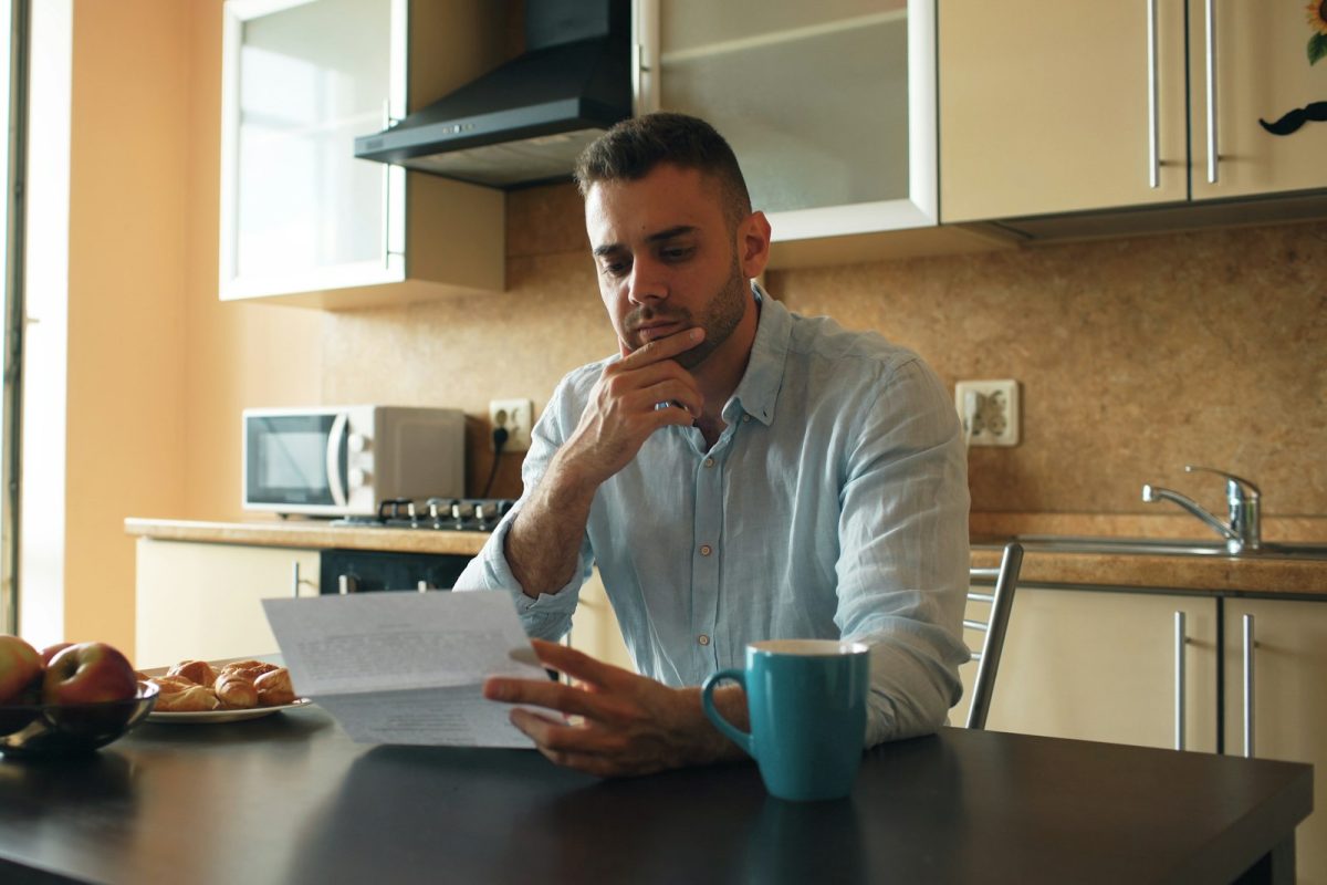 A man reading a letter at a kitchen table